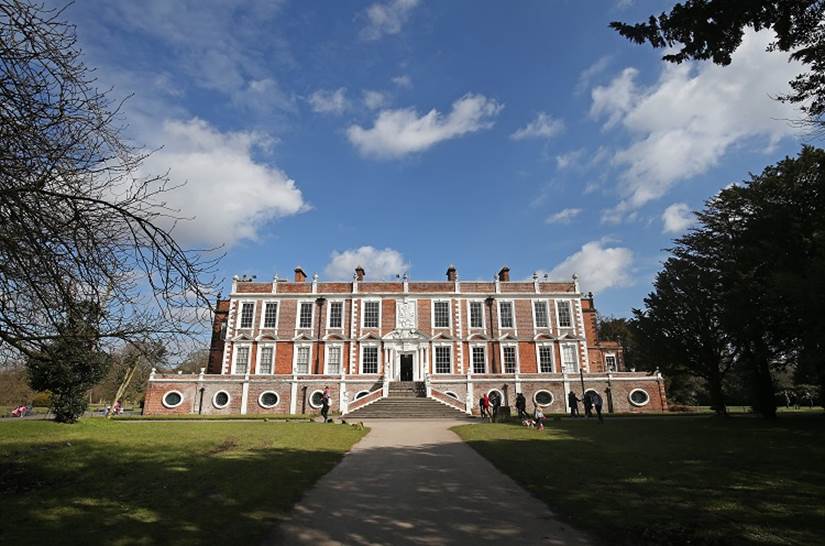 View of croxteth hall against the blue sky and white clouds with trees and gardens in front of the hall