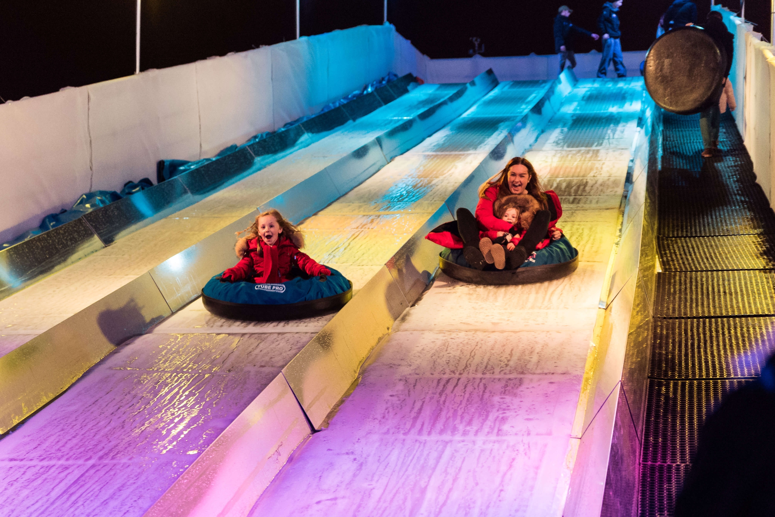 a lady and a young girl sliding down a slide with purple and blue lighting
