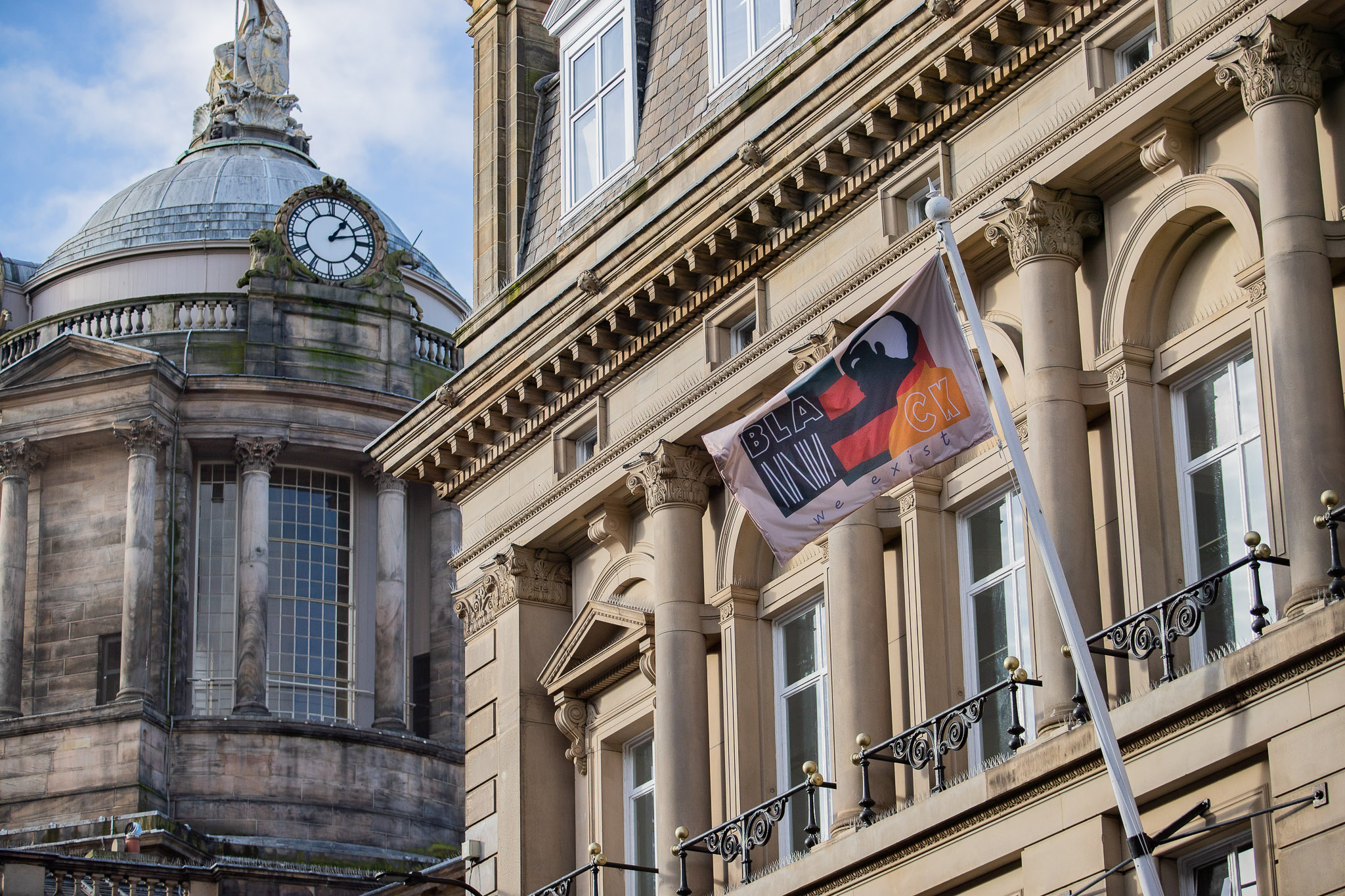 flag hanging on flagpole on side of building with liverpool town hall dome in background for dot-art project