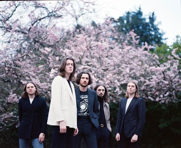 5 malaes standing in front of a pink blossom tree looking at camera for the music pilot