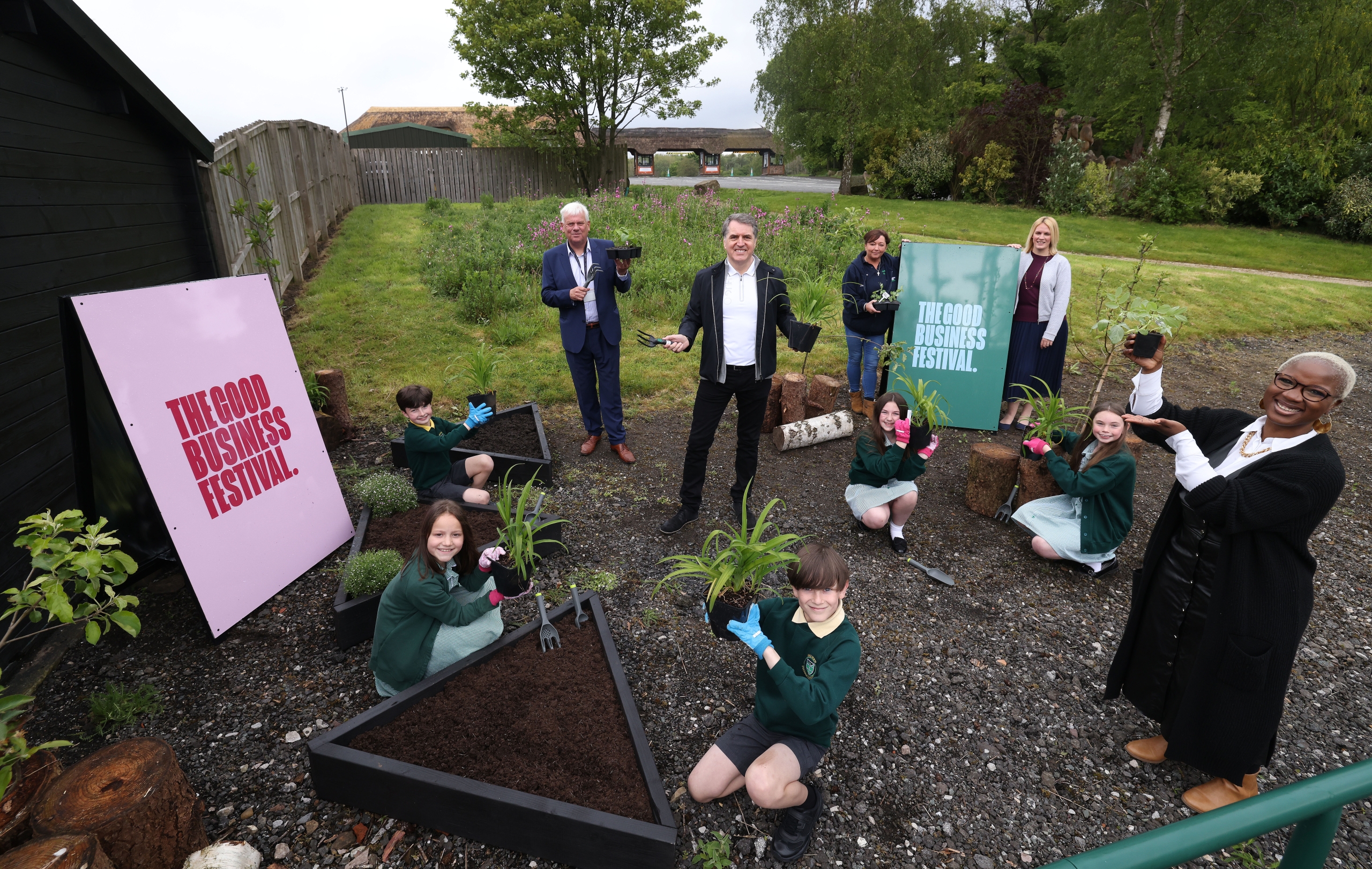 children sitting on the ground planting surrounded by good business festival branding on boards and metro mayor of liverpool
