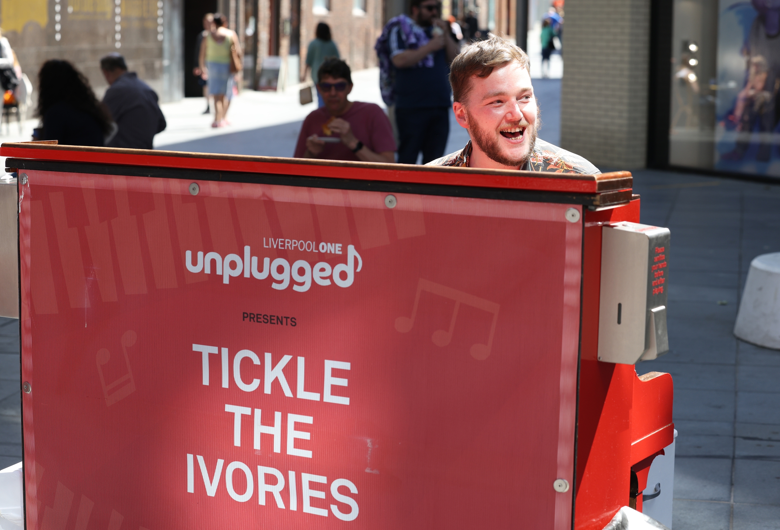 man smiling playing piano in liverpool one