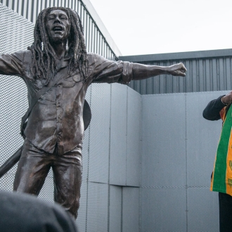 man stood next to bob marley statue happy