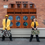 man and woman stood in yellow jackets and hats in front of wall