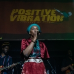 person stoof on stage with mircophone in front of sign that says positive vibration