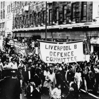 black and white photo of crowds protesting in liverpool holding a banner saying liverpool 8 defence committee