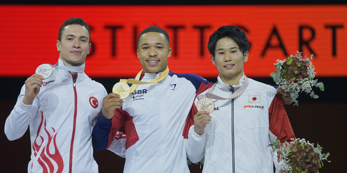 world gymnastic medal holders - three men in white gymnastics uniform holding their medals