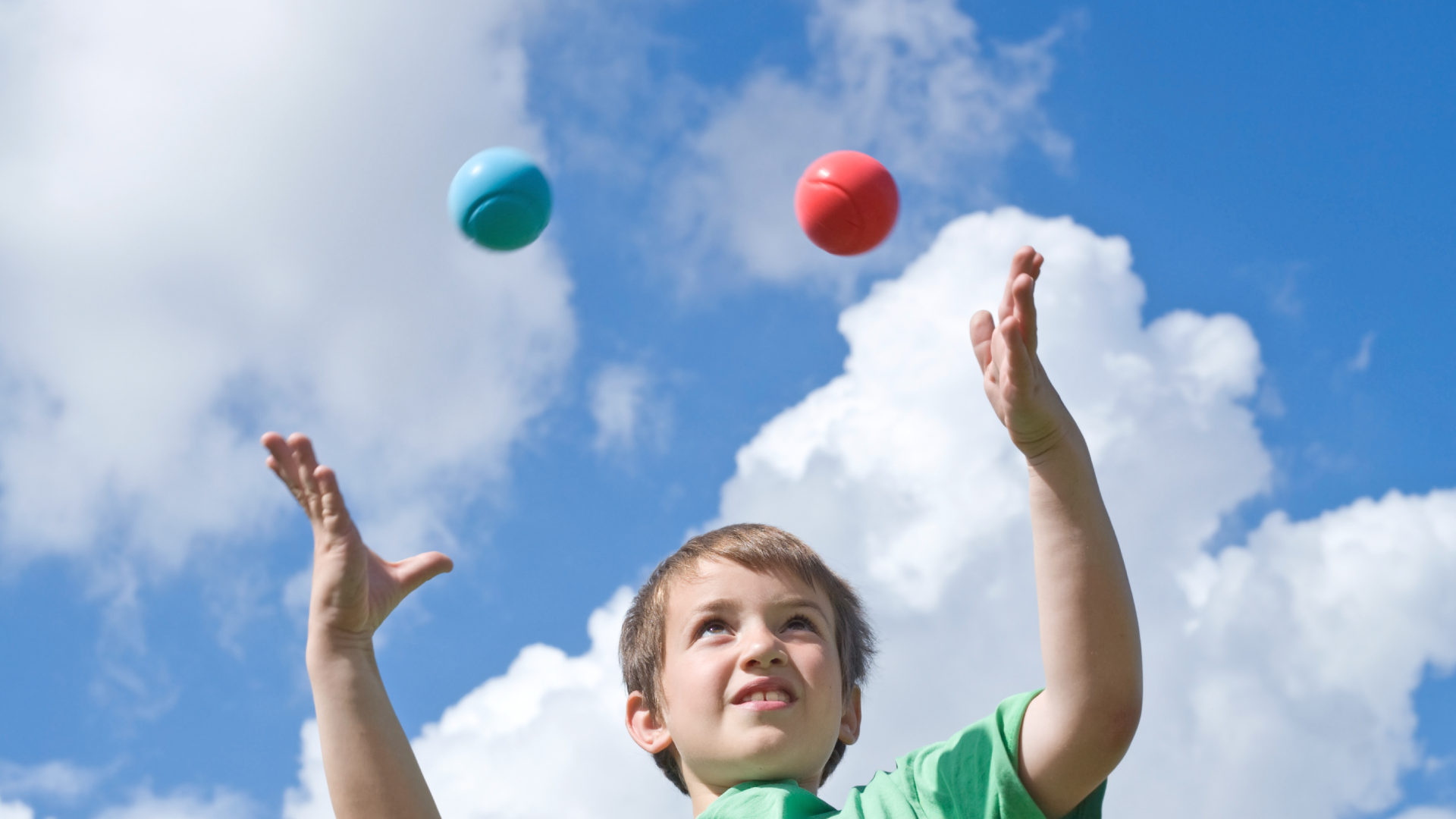 child juggling balls against a blue sky
