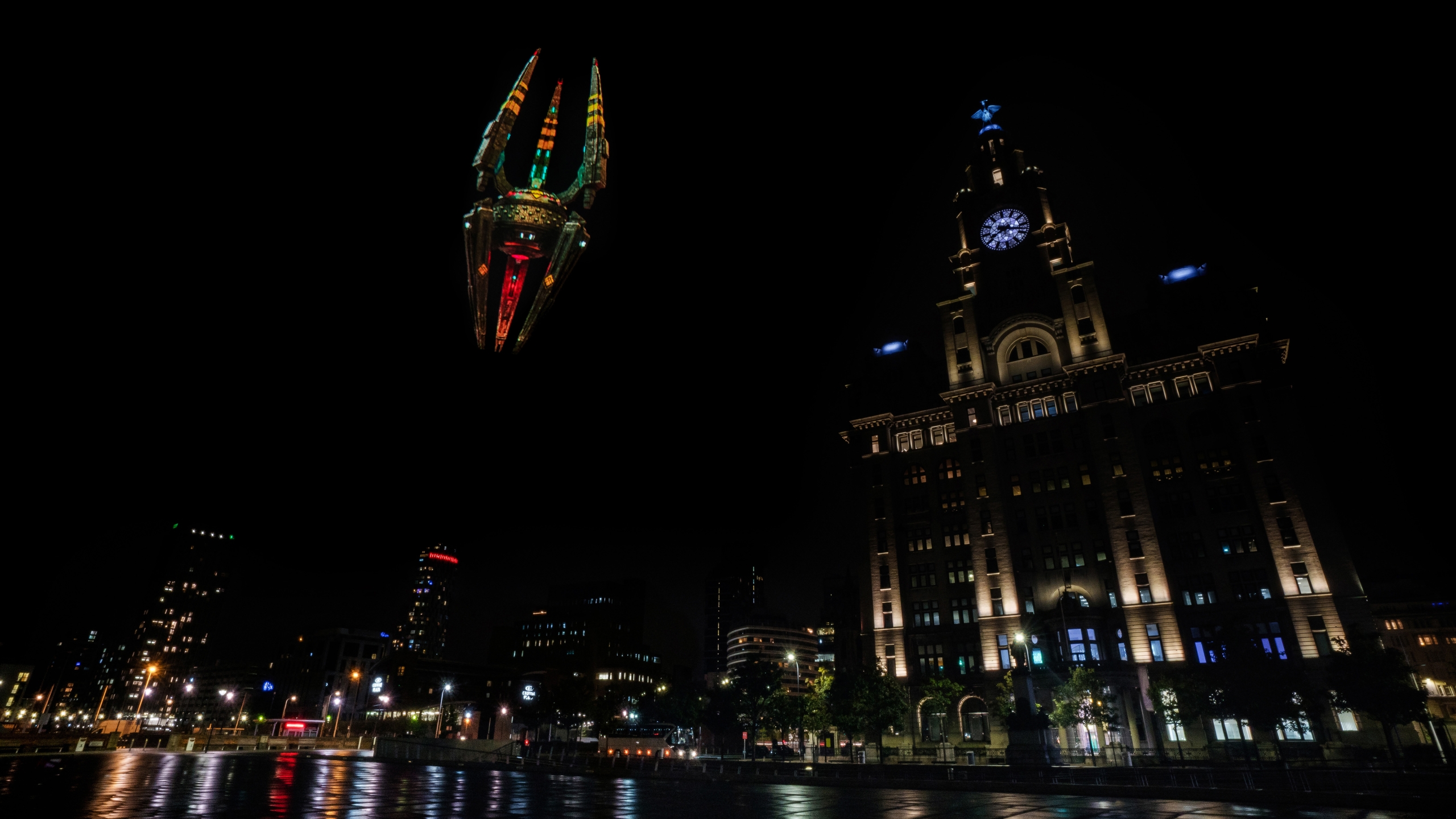 bbc spaceship projection on liverpool pier head at night with the liverpool liver building in the background