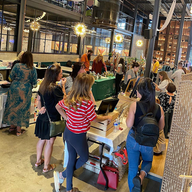 people all standing around tables in a christmas market