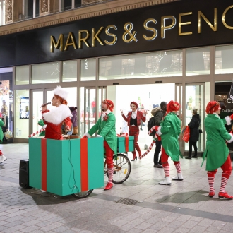 people dressed as elves performing in liverpool city centre outside marks and spencer