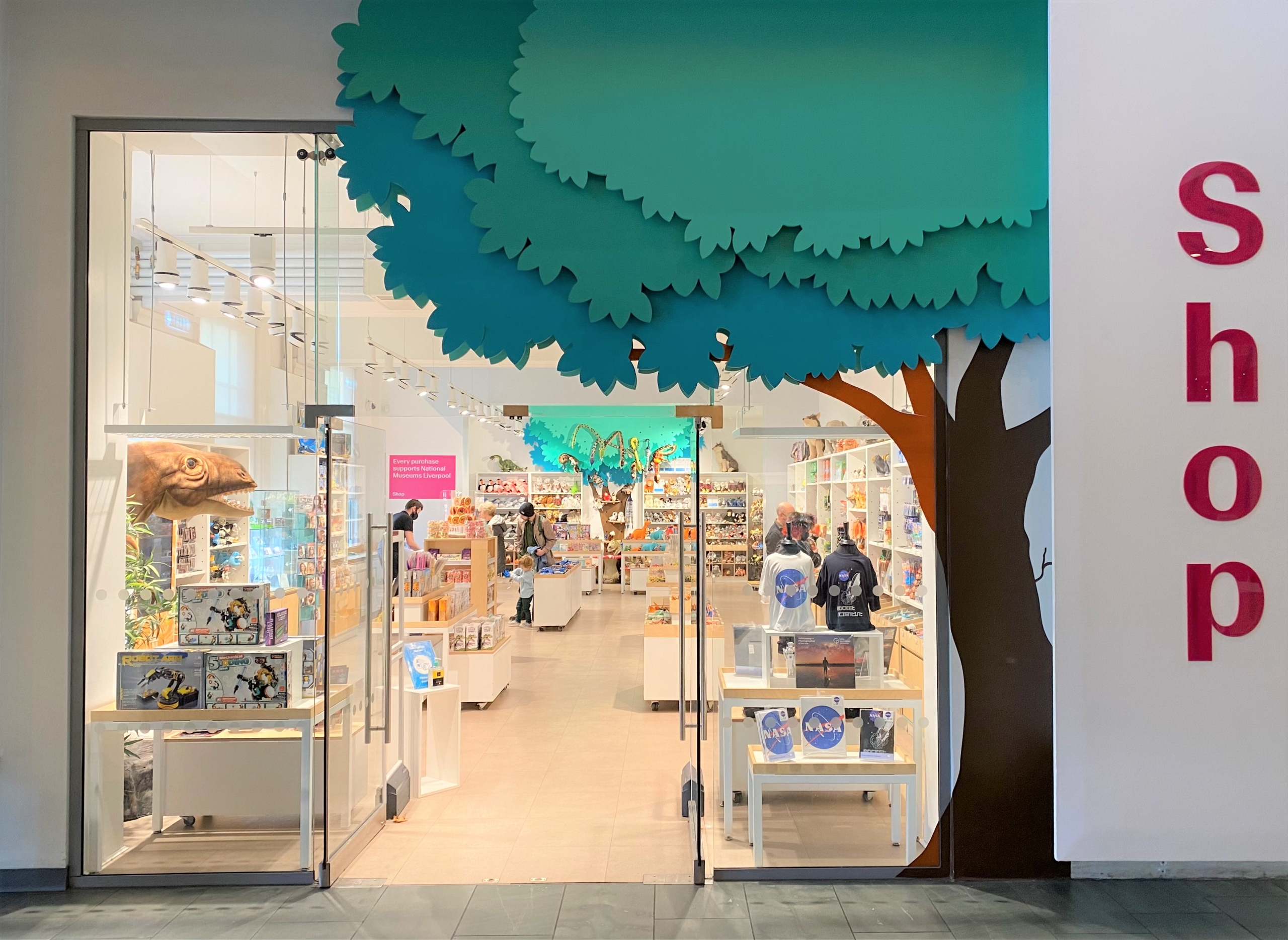 view of museum shop through a glass frontage and a giant cartoon tree outside showing christmas stock