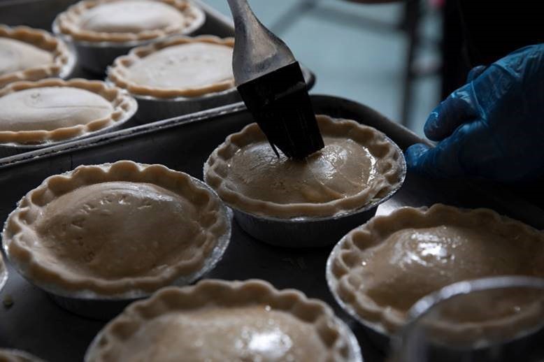 bakery pies in a tray being eggwashed