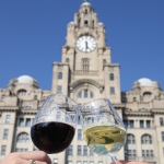 royal liver building with one hand holding a red wine glass and the other holding a white wine glass