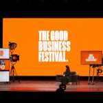 the good business festival set on stage with a person presenting against an orange backfdrop