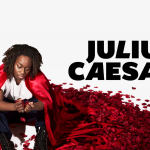 black actor in red cloak, white top and black pants sitting among red petals in a red cloak, black text says julius caesar