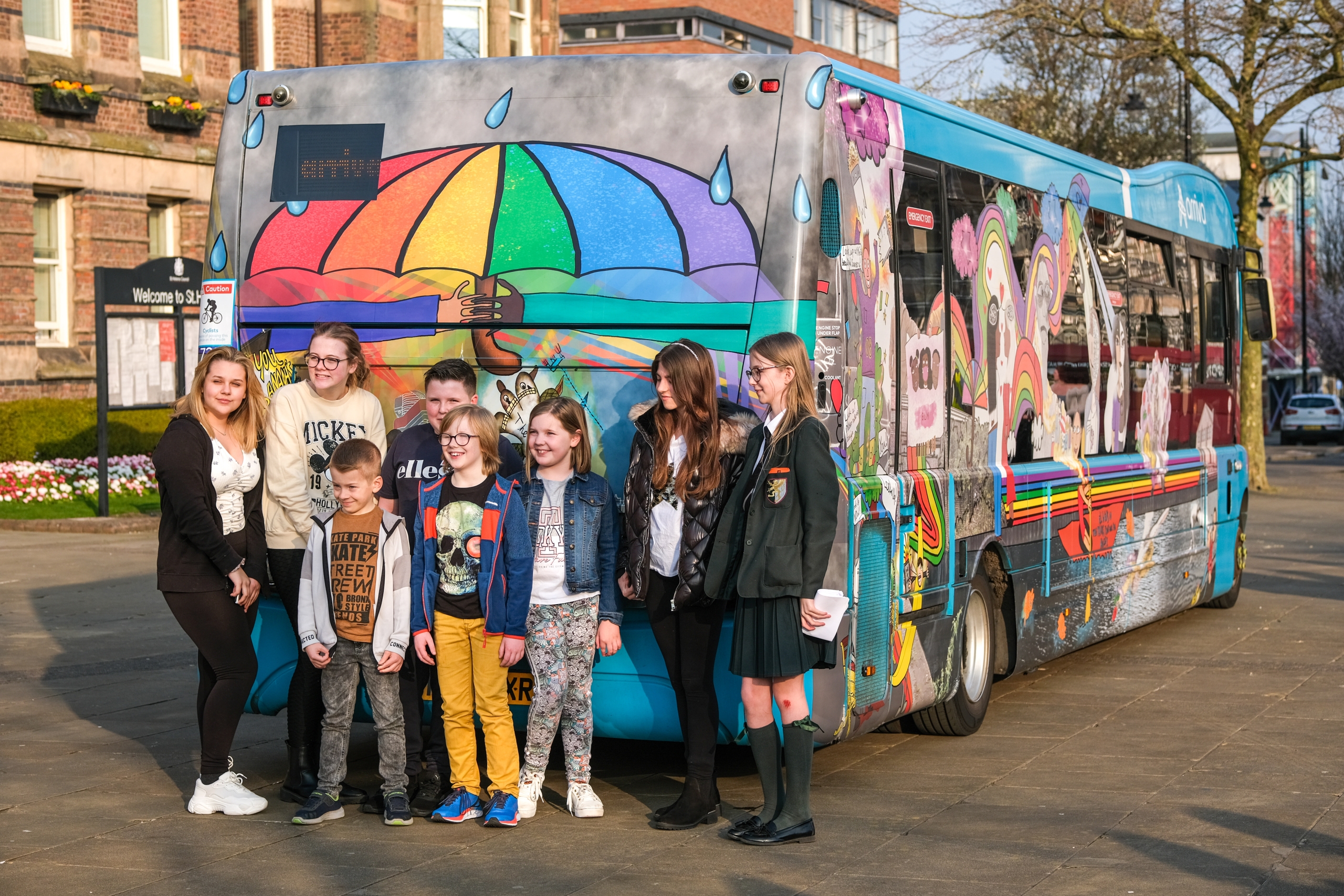 ARRIVA bus featuring colourful art over exterior with young people stood in front of bus
