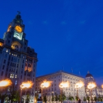 royal lliver building alongside cunard building at night with seven light up flames in front