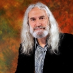 photograph of man with long grey hair, dark black jacket looking at camera for liverpool artist mural