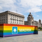 Large storage container painted in rainbow colours with maersk logo on side in front of cunard and port of liverpool buildings