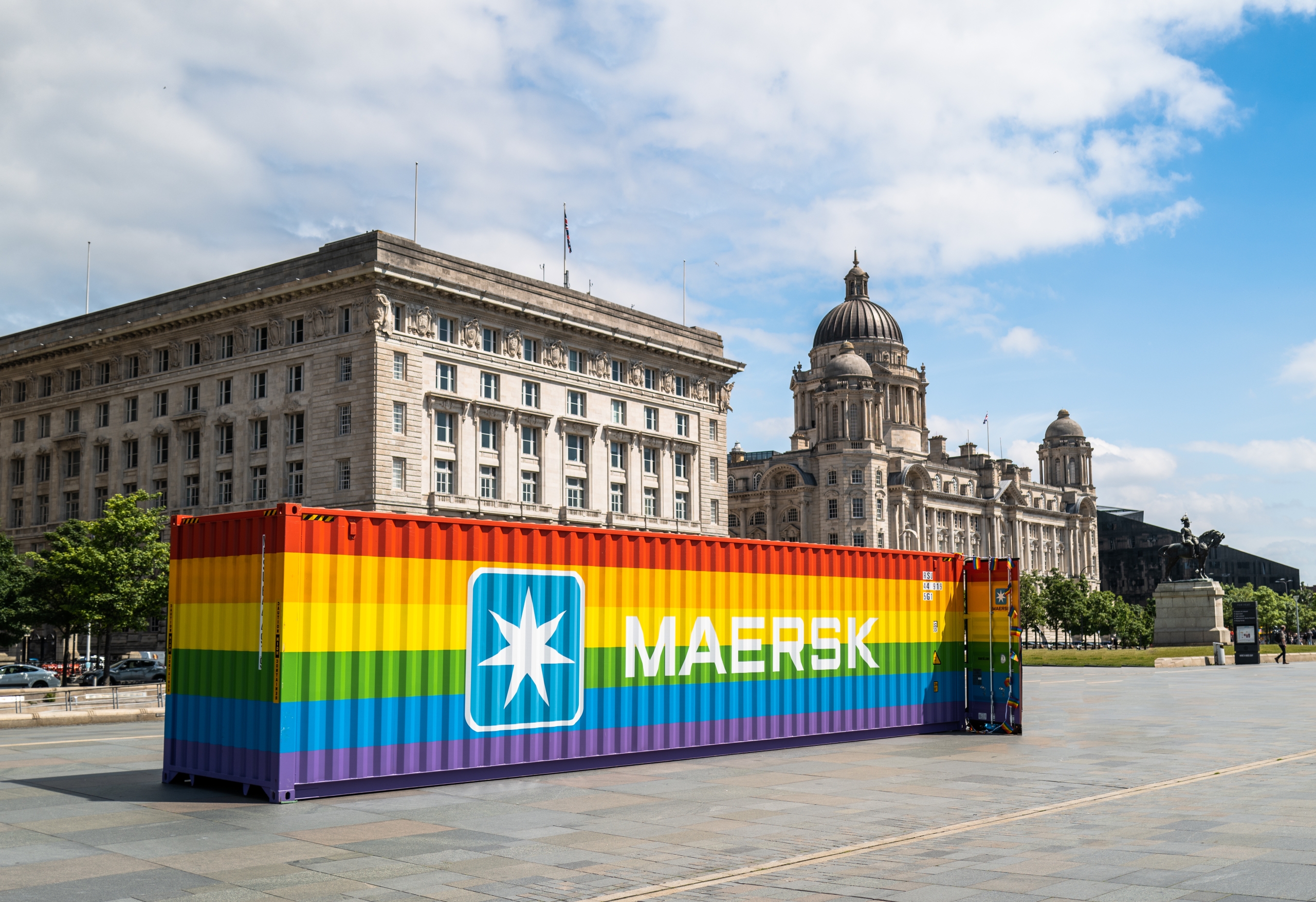 Large storage container painted in rainbow colours with maersk logo on side in front of cunard and port of liverpool buildings