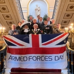 armed forces day flag held up by lord mayor and service personnel on the steps inside liverpool town hall