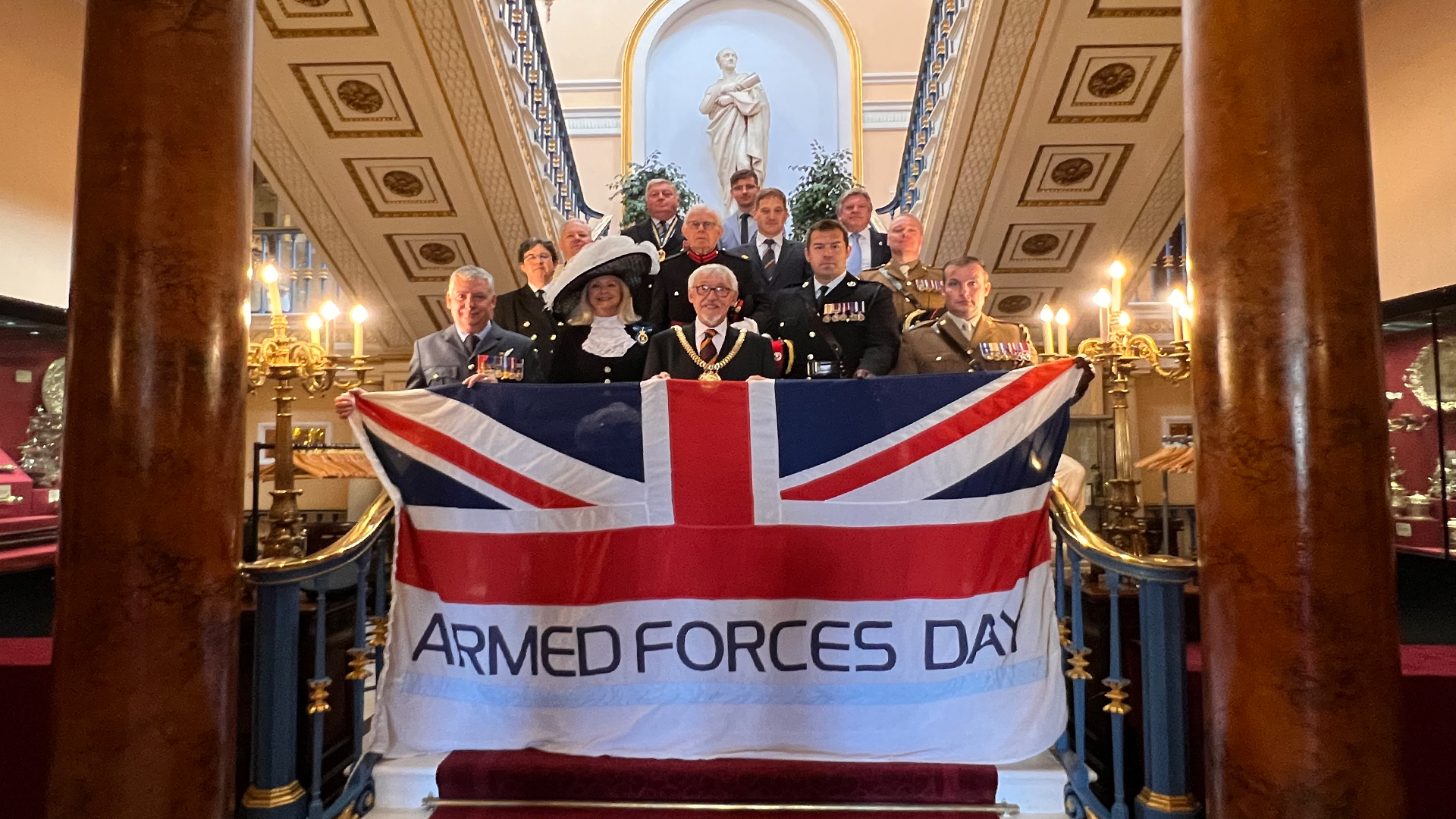 armed forces day flag held up by lord mayor and service personnel on the steps inside liverpool town hall