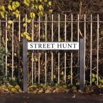street sign says street hunt in front of a park railing in st helens