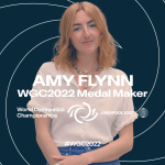 Amy Flynn against a blue backdrop with white swirls, white text says Amy Flynn WGC2022 Medal Maker for gymnastics championships