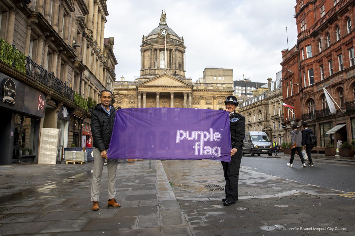 man and police woman holding a giant purple flag on castle street