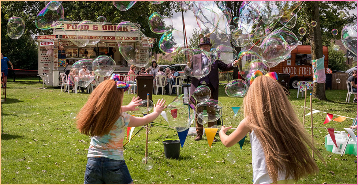 young girls delighted with large bubbles being blown at the Knowsley Flower Show Feel Good Festival