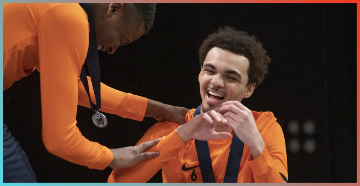 Two young people in orange tops interacting with each other and laughing