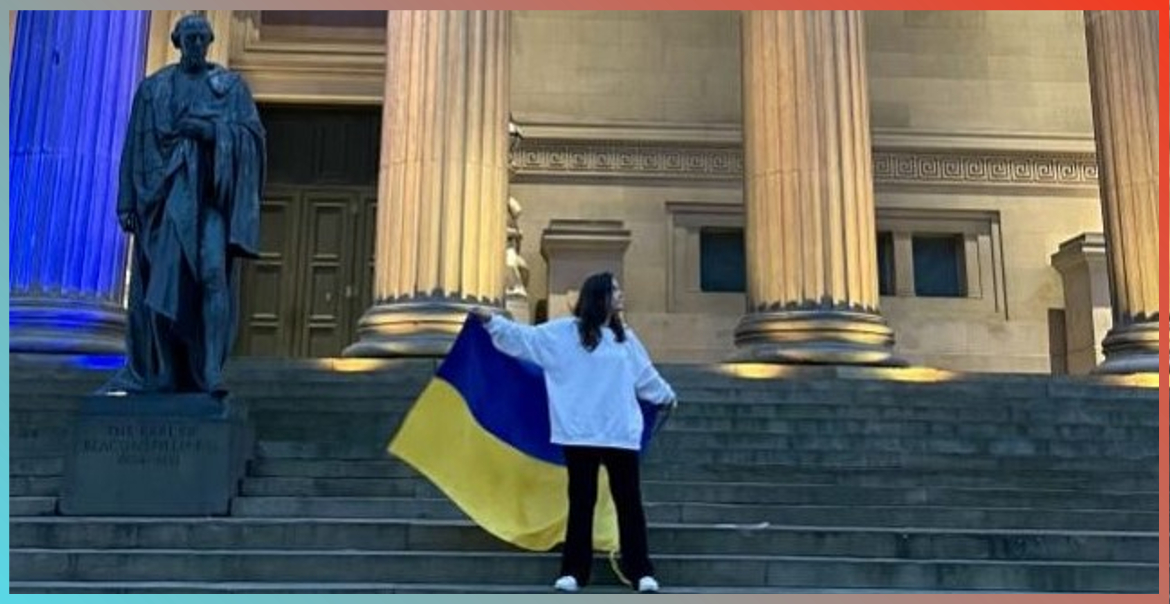 Events Project Assistant Veronika outside St Georges Hall in Liverpool holding the Ukrainian Flag