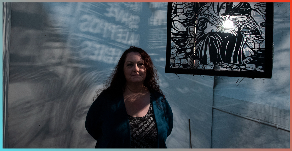 Pam Sullivan stood in front of a piece of artwork on the wall behind her.
