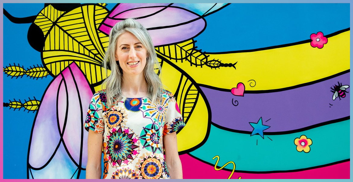 Caroline Daly stood in front of a brightly coloured wall.