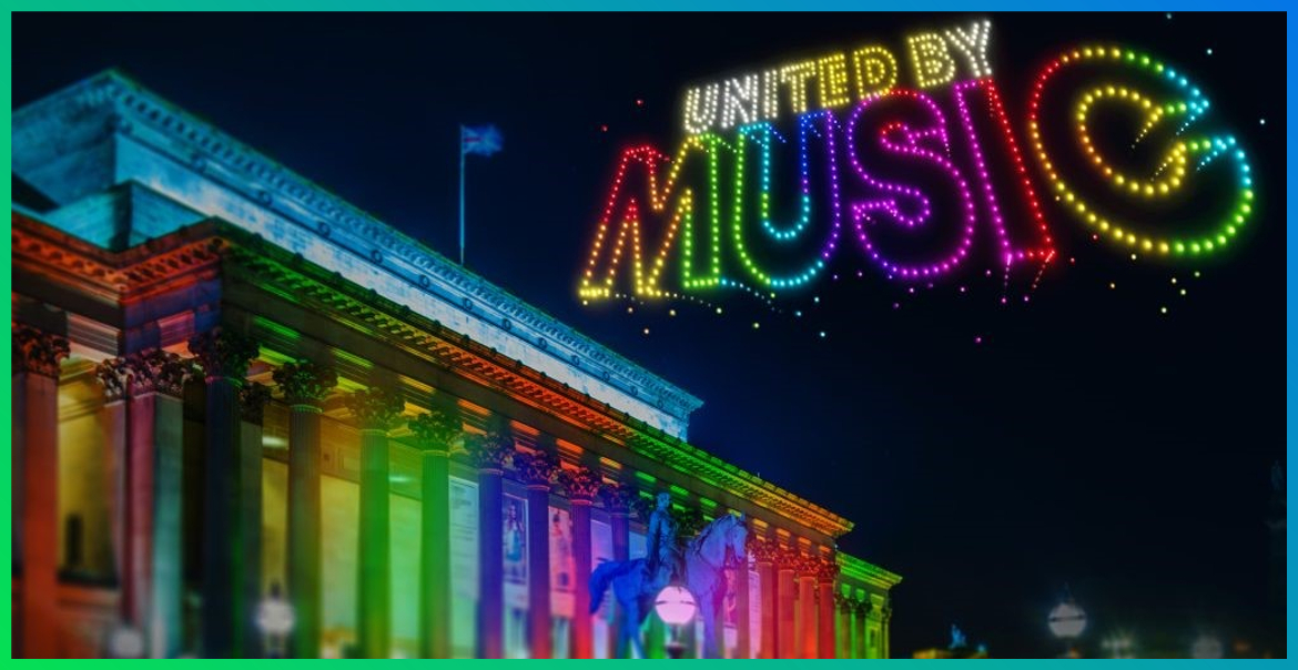 St Georges Hall lit up in rainbow colours with the text United By Music