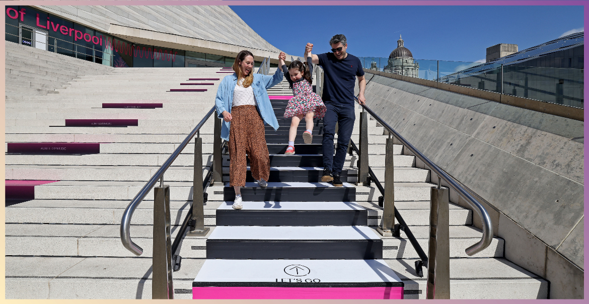 Parents lifting their little girl in the air on the interactive steps of the National Museum of Liverpool