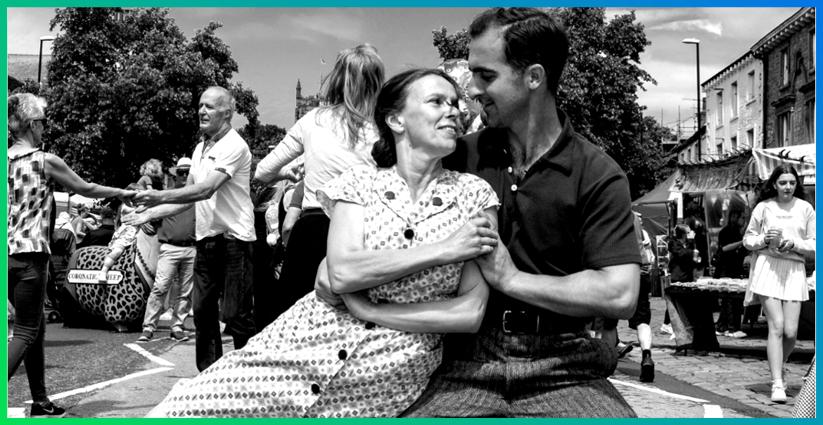 a man and woman dancing in the street to 1940s music