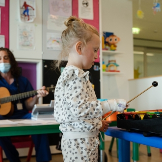 A pre-school aged child playing the xylophone.