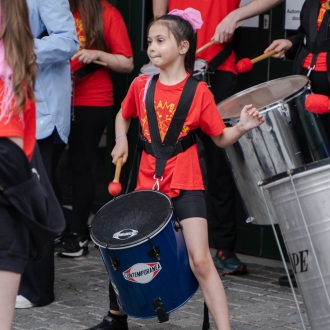 A young girl playing the drums in a street performance.