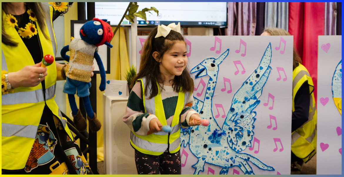 A pre-school child wearing a hi-vis next to an image of a Liver Bird.