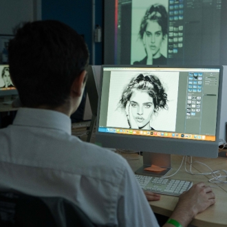 A pupil photoshopping an image of a woman on their computer screen.