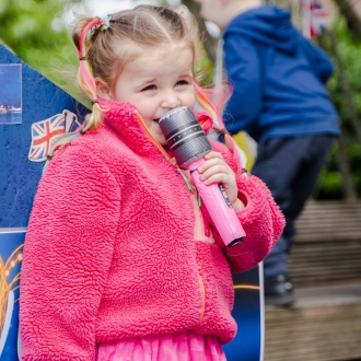 A pre-school aged child doing a Eurovision-themed performance outside.
