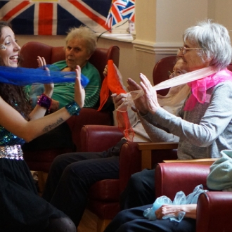 A woman engaging with a care home resident during a Eurovision themed performance.