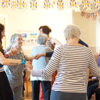 A woman engaging with a care home residents during a Eurovision themed performance.