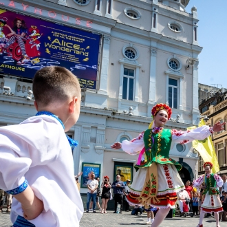 Performers wearing traditional dress and dancing in a street performance as part of Liverpool European Festival.