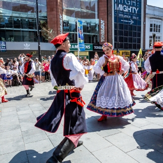 Performers wearing traditional dress and dancing in a street performance as part of Liverpool European Festival.