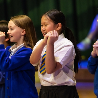 Primary school pupils on stage singing.