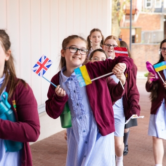 Primary school pupils waving handheld European flags.