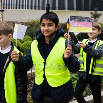 Primary school pupils waving handheld European flags.